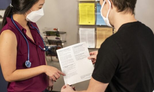 Clinician reviewing credentialing paperwork with a colleague in a medical office